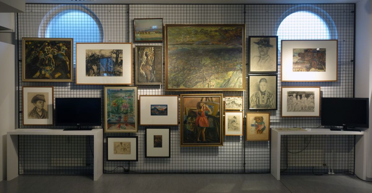 Verschiedene Werke des Künstlers Alfred Ahner hängen an einer Gitterwand